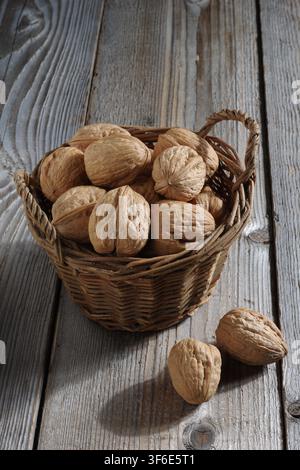 Walnuts in an old wicker basket on a wooden table Stock Photo