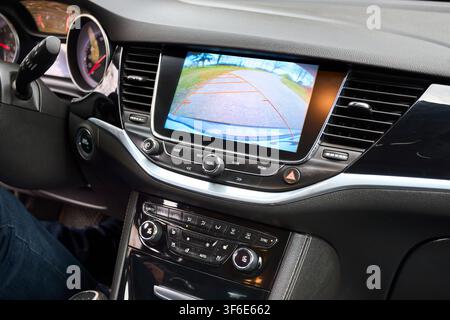 Modern car interior, dashboard close up view showcasing multimedia display showing rear view camera image parking assist lines climate control buttons Stock Photo