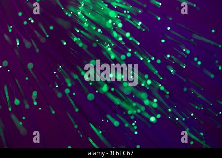Abstract green fiber optic strands and glowing light trails sweep across a deep purple background, creating a vivid high-speed technology, network, an Stock Photo