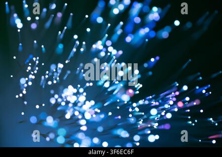Abstract blue fiber optic strands emit glowing points of light against a dark background, creating a vivid technology network concept with bokeh, data Stock Photo