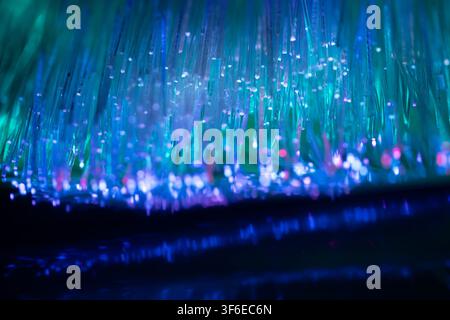 Close-up of luminous fiber optic strands with blue, teal, and violet light points, creating an abstract technology background for data, network, commu Stock Photo