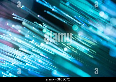 Abstract close-up of glowing fiber optic strands creating blue and turquoise light trails, illustrating high-speed data transmission, telecommunicatio Stock Photo