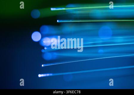 Abstract close-up of glowing blue and green fiber optic strands against a dark background, representing high-speed data transfer, telecommunications, Stock Photo