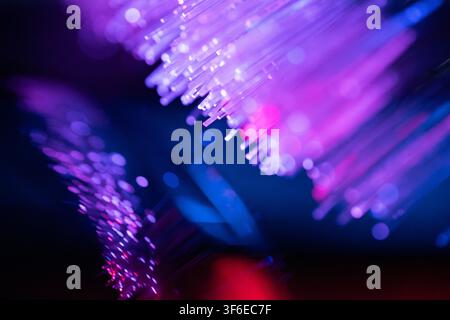 Abstract close-up of glowing fiber optic strands in neon purple, pink and blue hues, creating a vibrant technology background for data, communication Stock Photo