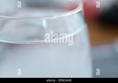 Close-up view of a transparent glass filled with cold sparkling water featuring tiny effervescent bubbles rising inside the clear liquid and condensat Stock Photo