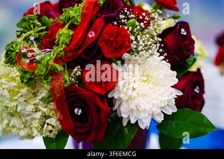 Bouquet with red roses, white chrysanthemums, and other flowers placed on a table. The setting looks colorful and festive for an occasion. Stock Photo