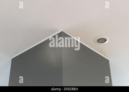 A minimalist architectural detail featuring a sharp corner where two walls meet, illuminated by a ceiling light Stock Photo