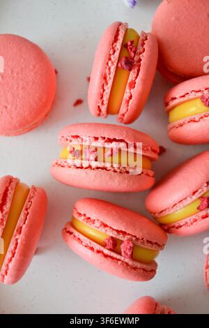 Pink french macarons decorated with yellow cream and dried berry pieces on a white background Stock Photo