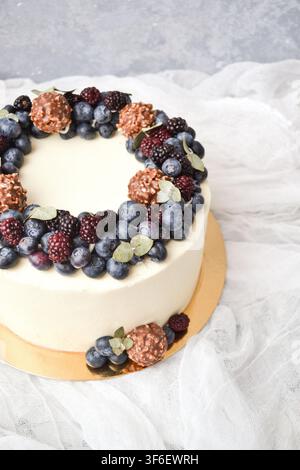 Close-up view of a frosted cake decorated with a ring of fresh berries and chocolate truffles Stock Photo