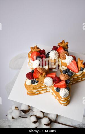 Star shaped layer cake decorated with strawberries, raspberries, meringue kisses, and cookies Stock Photo
