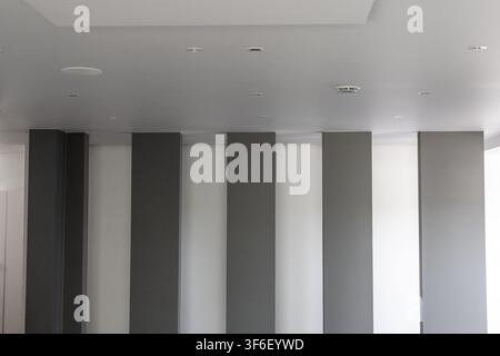 A contemporary architectural space features a repeating pattern of dark gray and white vertical wall panels creating a striking visual effect Stock Photo