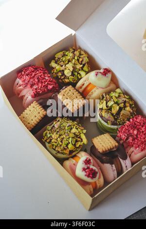 Craft gift box filled with decorated French macarons pistachio freeze dried berries and biscuits Stock Photo