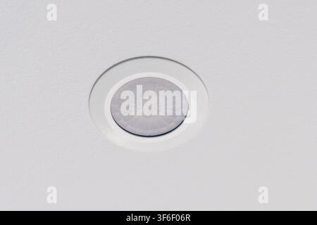 A modern recessed light fixture is installed on a textured white ceiling, providing soft and diffused light to the room Stock Photo