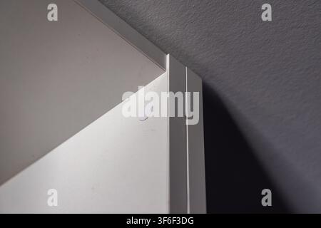 Minimalist composition highlighting the intersection of a smooth white panel and a rough grey wall with subtle lighting and shadow Stock Photo