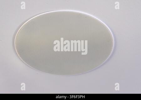 A detailed view of a round speaker cover, showcasing its perforated surface and metallic texture against a plain background Stock Photo