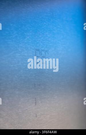 Abstract macro shot featuring finely etched characters and symbols on a textured metallic plane, illuminated by a soft blue gradient Stock Photo