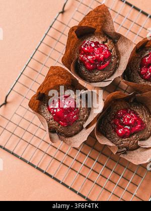Freshly baked chocolate muffins filled with red berry cherry jam in Tulip paper liners Stock Photo