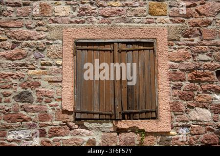 Vintage Closed Wooden Window Shutters on Rustic Red Stone Wall Stock Photo