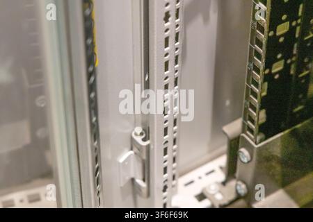 Detailed view of perforated metal rails and a circuit board within a data center cabinet Stock Photo