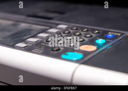 Detailed view of a multi-function device control panel featuring a numeric keypad, function buttons, and glowing indicator lights Stock Photo
