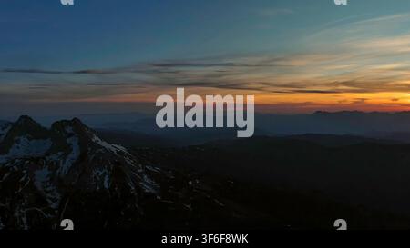 Rocky snow mountains at sunset aerial Stock Photo