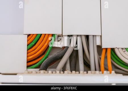 A close-up view reveals a variety of colored network cables, including orange, green, and gray, organized within a white junction box for efficient co Stock Photo