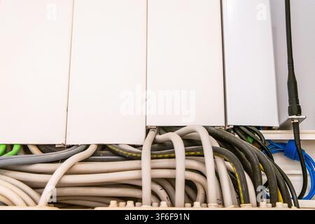 A close-up view of various electrical and data cables bundled together within a clean, modern housing unit Stock Photo