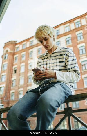 Man Using Smartphone and Earphones Outdoors Stock Photo