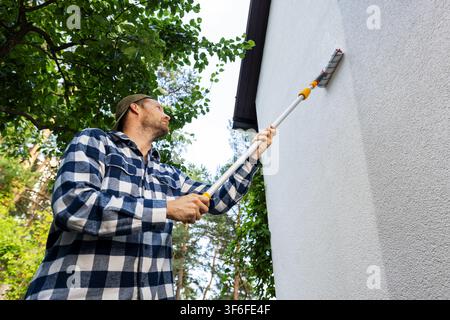 house painter restore paint on building exterior with roller Stock Photo