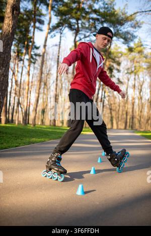 Lower body view of a skater rolling around blue cones on a path Stock Photo