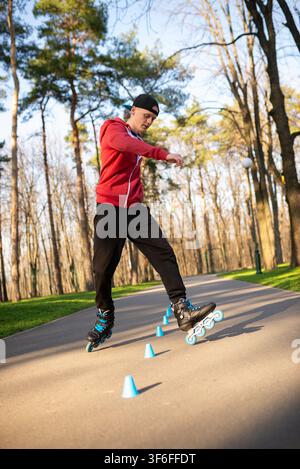 A skater rolling around blue cones on a path Stock Photo