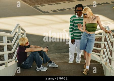 Diverse People Using Smartphones Outdoors on Stairs Stock Photo