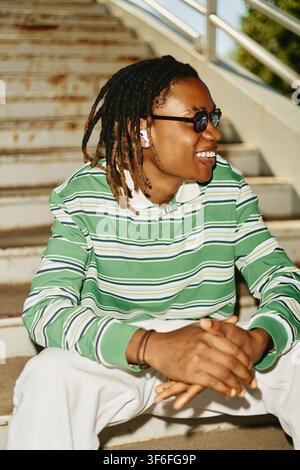 Happy Black Man with Dreadlocks Sitting on Stairs Outdoors Stock Photo