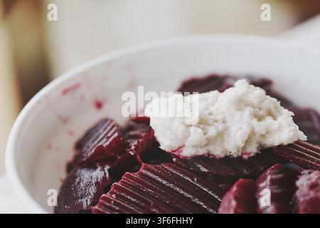 Close-up view of a healthy homemade beetroot salad served in a white bowl with a dollop of pungent freshly grated horseradish sauce on top for a flavo Stock Photo