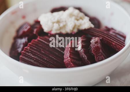 A close-up shot of a healthy vegetarian beetroot salad topped with freshly grated white horseradish in a white ceramic bowl. Stock Photo
