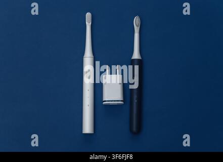 Electro-toothbrushes with charger on classic blue background. Color 2020. Top view Stock Photo