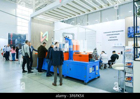 Moscow, Russia, 09.07.2026 Men inspecting industrial cable manufacturing machine at trade show exhibition. Professionals exploring new wire production Stock Photo