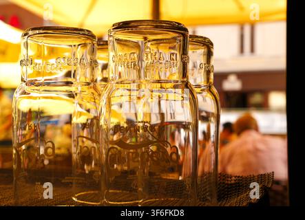 Clean empty beer glasses stored upside down on a outdoor bar counter in warm sunlight. Stock Photo