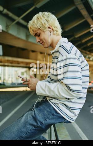 Man Using Smartphone and Earphones Outdoors Stock Photo