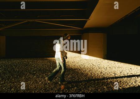 Man with Headphones Walking Outdoors under Bridge Stock Photo