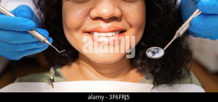 Closeup of smiling black female patient during dental examination with professional instruments Stock Photo