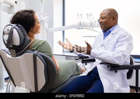 Black male dentist explaining treatment options to female patient in dentistry clinic Stock Photo