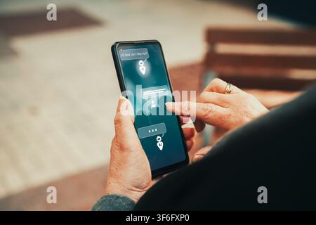 Mature woman chatting with AI chatbot assistant on smartphone screen. Artificial intelligence adoption, virtual assistants, and technology. Stock Photo