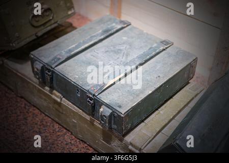 Weathered metal storage box with open lid on wooden surface, displaying rugged texture, slight discoloration, and visible screws, set against soft blu Stock Photo