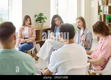 College students in circle discussing ideas at classroom meeting for teamwork Stock Photo