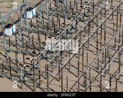 Aerial view of an electrical substation with high-voltage equipment, metal structures, and insulators on a gravel ground in the Netherlands. Stock Photo