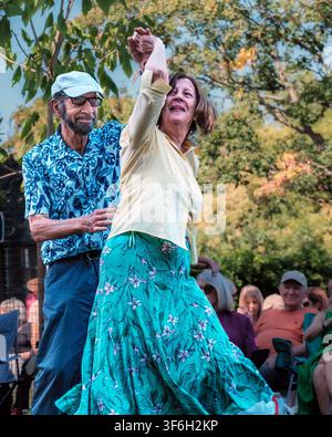 A senior couple dance together at an open-air summer concert in Pinner Memorial Park, Pinner, London, England, UK. Stock Photo