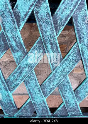 Weathered turquoise wooden lattice with a repeating crisscross pattern in close-up Stock Photo