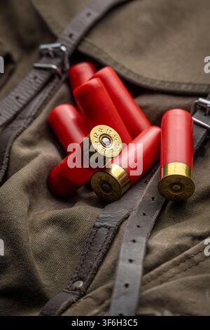 Red 12 gauge shotgun shells lying on a vintage canvas hunting backpack. Stock Photo