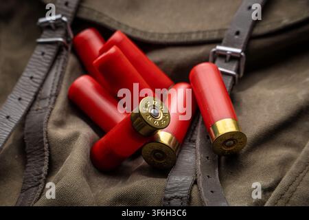 Red 12 gauge shotgun shells lying on a vintage canvas hunting backpack. Stock Photo